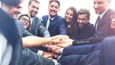 Équipe de professionnels se joignant les mains en cercle.