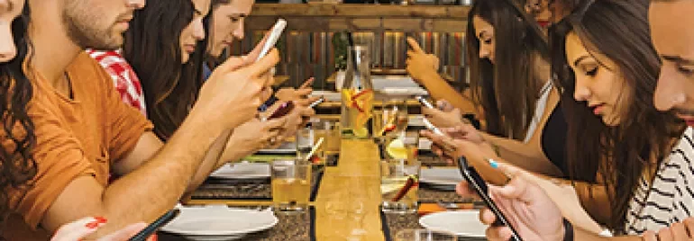 Groupe de personnes assises à une longue table utilisant des smartphones.